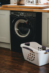 Photo of a black washing machine with a laundry basket in front